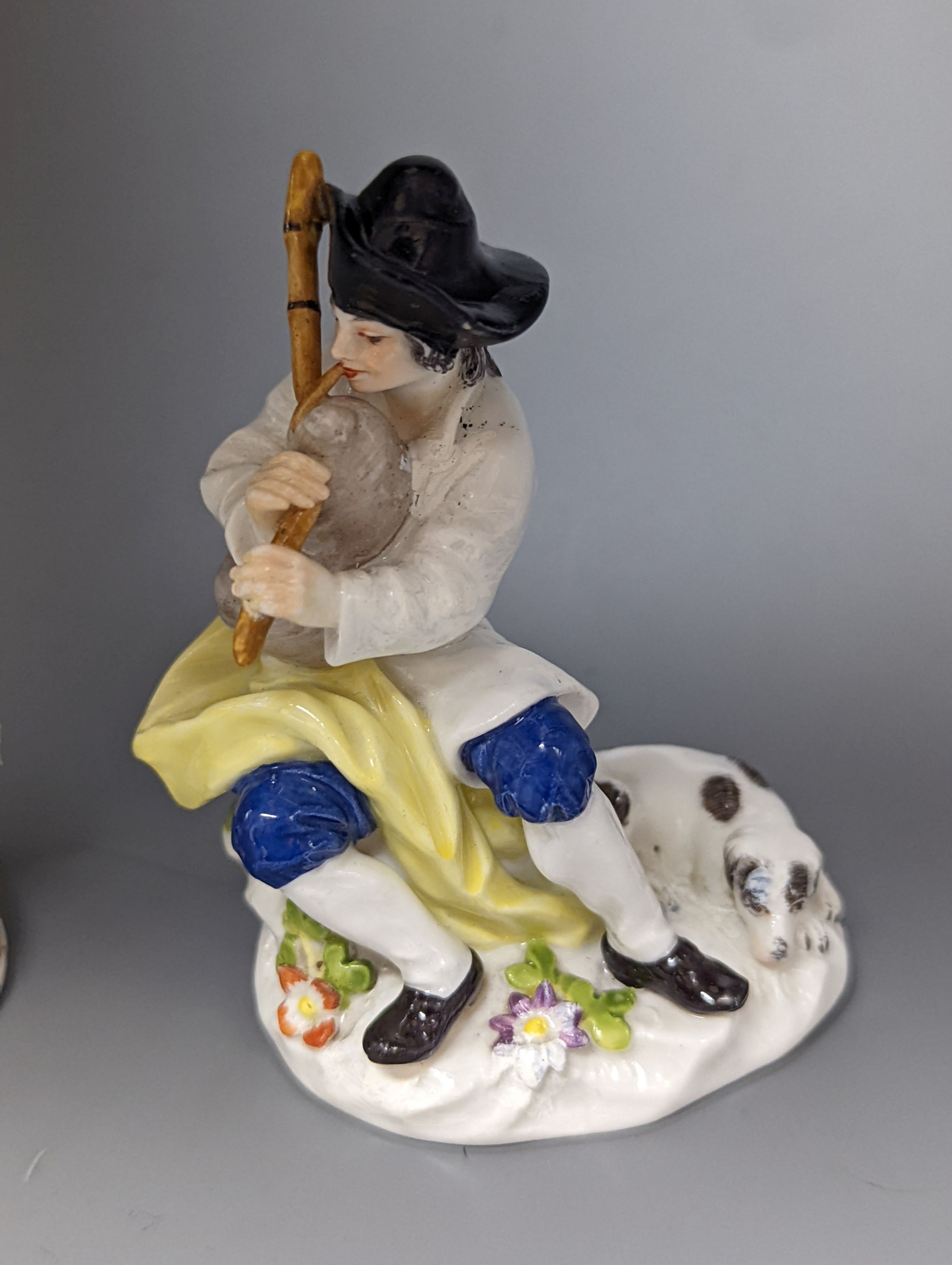 A Meissen figure of a seated man playing the bagpipes, 8.5cm., and a similar group of a huntswoman with a hound, 13cm., late 19th century, 8.5 cm and 13 cm high, some restoration